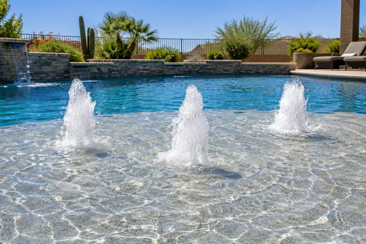Three bubbler fountains splashing on a pool sun shelf, sparkling water, sunny day